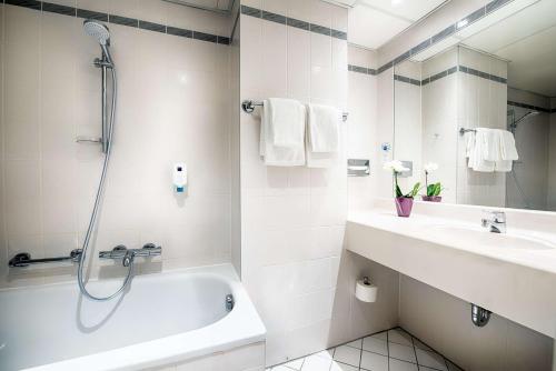 ein Badezimmer mit einer Dusche, einem Waschbecken und einer Badewanne in der Unterkunft Congress Hotel Chemnitz in Chemnitz