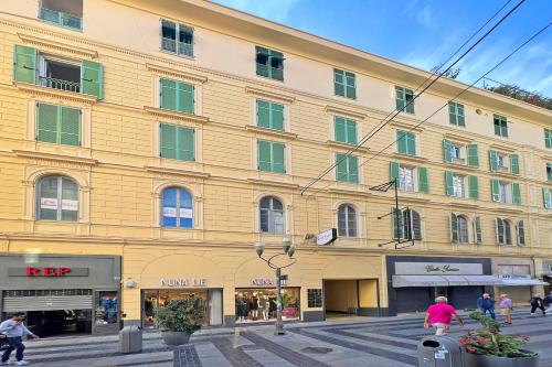 a large yellow building with people walking in front of it at Boutique Central Apartments- Happy Rentals in Sanremo