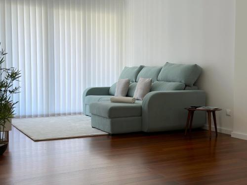 un sofá azul sentado en una sala de estar en Tropical Garden, en Caniço