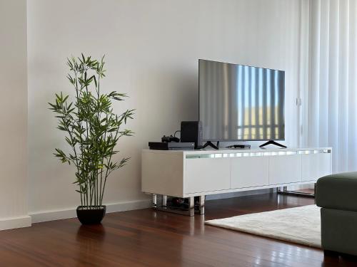 a living room with a tv on a white table at Tropical Garden in Caniço