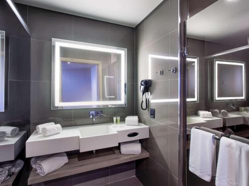 a bathroom with two sinks and two mirrors at Novotel Itu Terras de São José Golf & Resort in Itu