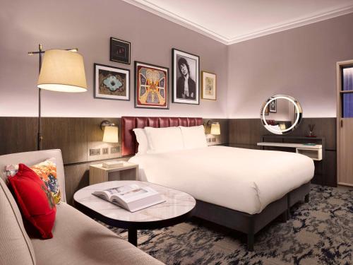 a hotel room with a bed and a table and a couch at The Trafalgar St. James, London Curio collection by Hilton in London