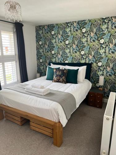 a bedroom with a large bed with floral wallpaper at Divers Cottage - Central Whitstable in Whitstable