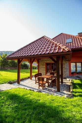 a wooden pavilion with a table and benches in a field at Siedlisko Leszczyny in Kunkowa