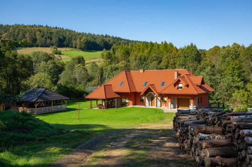 a house with an orange roof on a green field at Siedlisko Leszczyny in Kunkowa