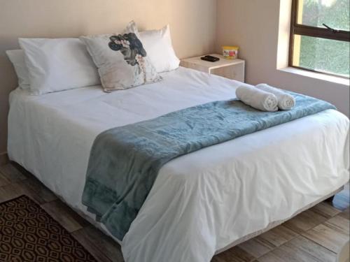 a large white bed with a blue blanket on it at Hopslot Villa in Mossel Bay