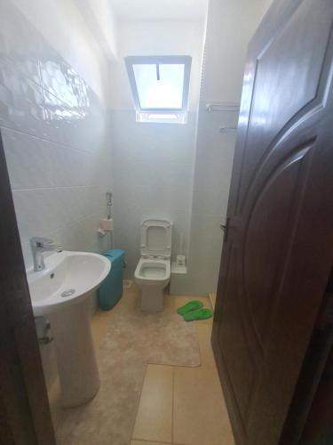 a bathroom with a sink and a toilet and a window at Emily Apartments Kisumu on Hatupe Enterprises Ltd Building in Kibos