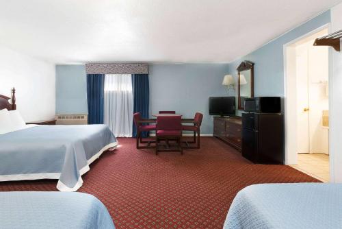 a hotel room with a bed and a table and chairs at Travelodge by Wyndham Las Vegas NM in Las Vegas