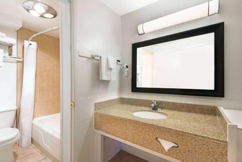 a bathroom with a sink and a toilet and a mirror at Travelodge by Wyndham Las Vegas NM in Las Vegas