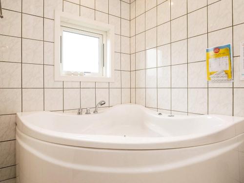 a white tub in a tiled bathroom with a window at 8 person holiday home in Lemvig in Lemvig