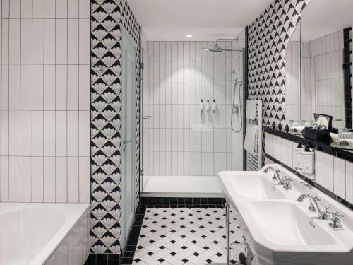 een witte badkamer met een bad, een wastafel en een bad bij Le 1932 Hotel & Spa Cap d'Antibes - MGallery in Juan-les-Pins