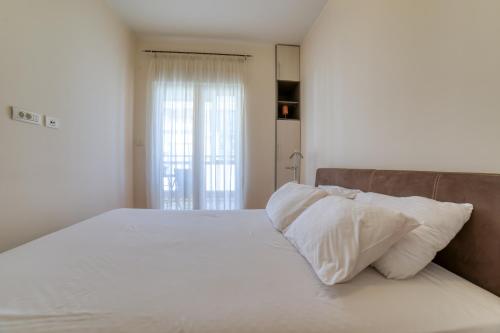 um quarto com uma cama grande com lençóis brancos e almofadas em Gold apartman em Podgorica