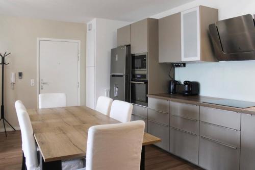 uma cozinha com uma mesa de madeira e cadeiras brancas em Large cosy nest with balcony in Aubervilliers em Aubervilliers
