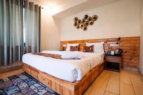 a bedroom with a large bed with a wooden headboard at Aaryam Resort, Auli in Joshīmath