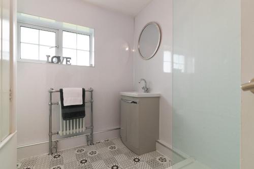 une salle de bain blanche avec un lavabo et un miroir dans l'établissement Harleys Way - Short Walk to Beach and Village, à Saundersfoot