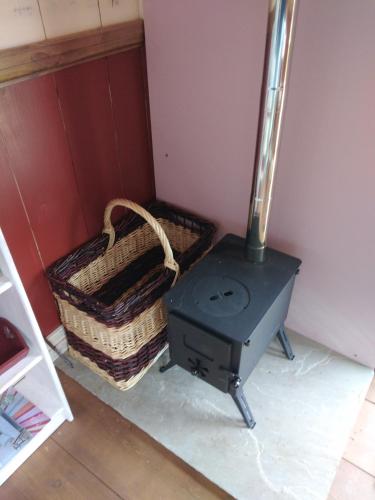 a stove in a room with a basket next to it at Shirehill Farm, Shires Barns in Chippenham