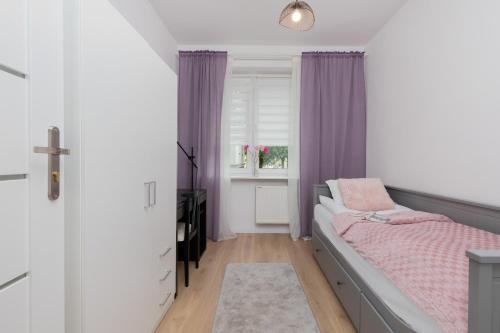 a bedroom with a bed and a window with purple curtains at Beautiful & Comfortable Spacious Apartment in Gdansk by Renters in Gdańsk