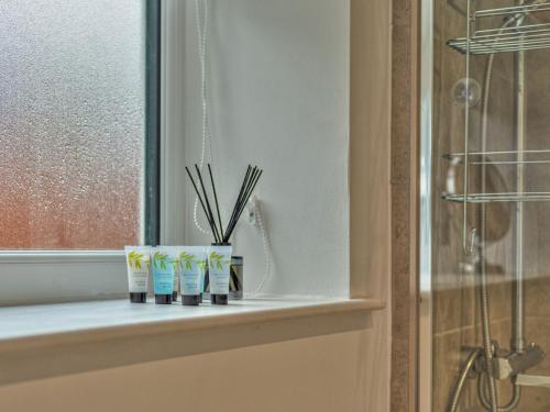 a bathroom window sill with three toothbrushes and pens at Pass the Keys Modern Apartment With Courtyard in Madeley