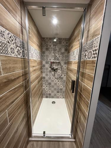 ein Bad mit einer Dusche und Holzwänden in der Unterkunft Au 35 in Millau
