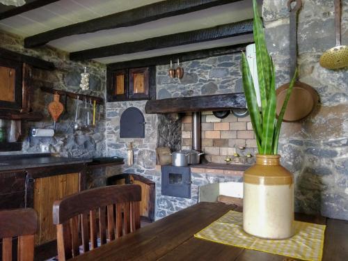 a kitchen with a wooden table with a vase with a plant at Achadinha - Mountain Cottage in Arco da Calheta