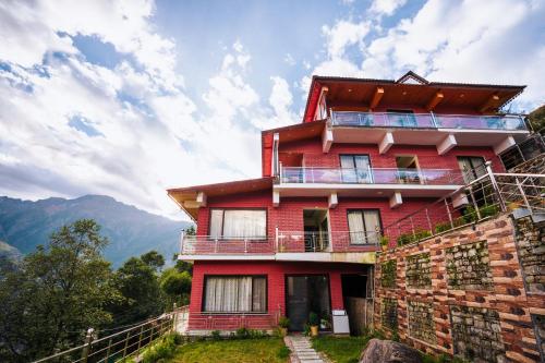 ジョシマットにあるAaryam Resort, Auliの山を背景にした丘の上の赤い家