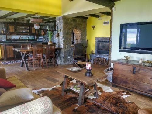 a living room with a table and a stone fireplace at Achadinha - Mountain Cottage in Arco da Calheta