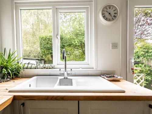 a kitchen with a sink and a clock on the wall at Pass the Keys Bright, comfortable 3 bed home with garden & parking in Ottery Saint Mary