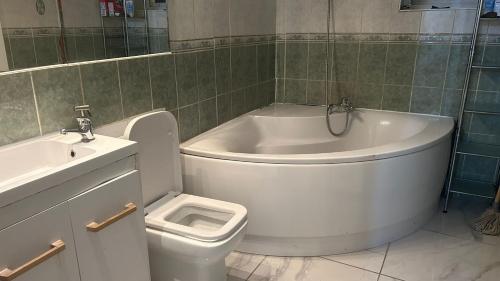 a bathroom with a tub and a toilet and a sink at Home Away in a Close in Thamesmead