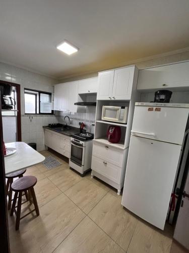 een keuken met een witte koelkast en een tafel bij Apartamento cidade ocian Praia Grande in Praia Grande