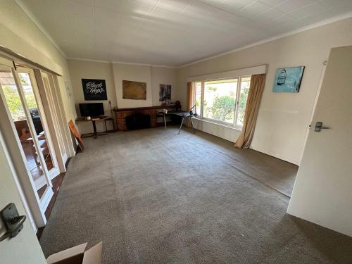 uma sala de estar vazia com televisão e janelas em Chimu Home-Hostel em Perth