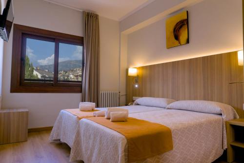 a hotel room with two beds and a window at Hotel Boltaña Ordesa in Boltaña