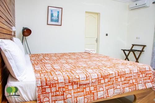 a bedroom with a bed with an orange and white blanket at VILLA DE L'INTEGRATION in Ouagadougou