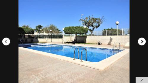uma grande piscina com água azul em CANET PLAYA MAGNIFICO APTO FAMILIAR con PISCINA y GARAJE em Canet d'En Berenguer