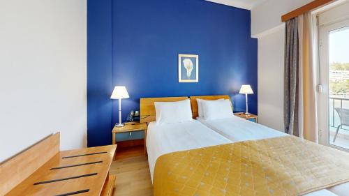 a bedroom with a large bed and a blue wall at Lucy Hotel in Chalkida
