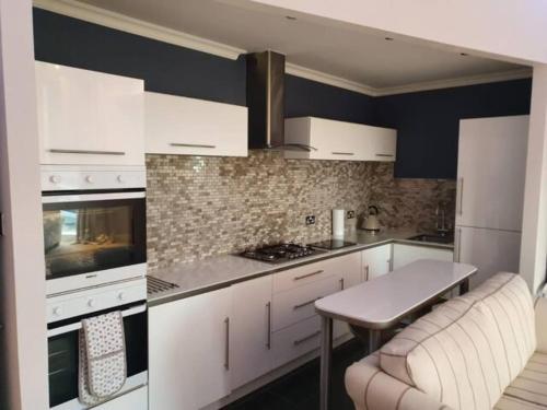 a kitchen with white cabinets and a table in it at Northcliffe Sea View in Sunderland