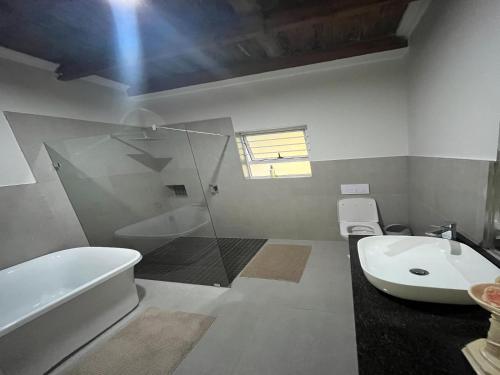 La salle de bains est pourvue d'une baignoire, d'un lavabo et de toilettes. dans l'établissement Homestead Bed and Breakfast, à Addo
