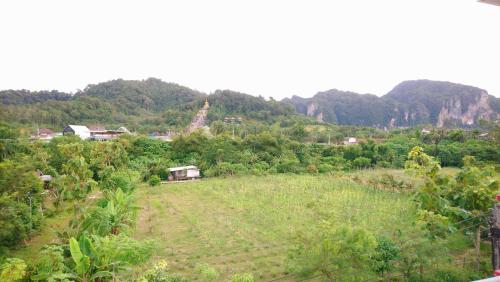 un campo de hierba con montañas en el fondo en TG Apartment Aonang en Ao Nang
