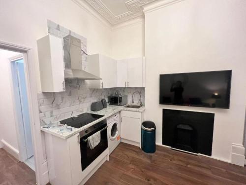 a white kitchen with a stove and a microwave at Iconic One Bed Apartment in Chiswick in London