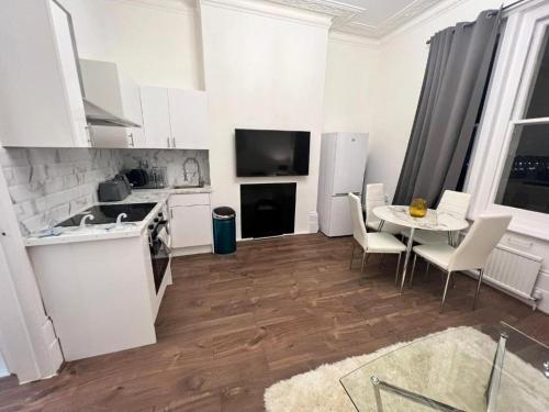 倫敦的住宿－Iconic One Bed Apartment in Chiswick，厨房配有白色橱柜和桌椅