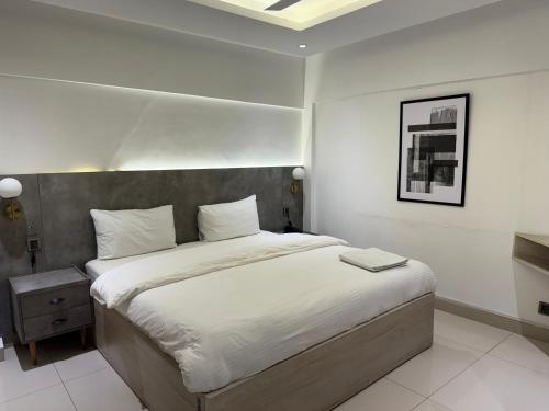 a bedroom with a large bed with white sheets at Hamsun Apart Hotel Clifton in Karachi