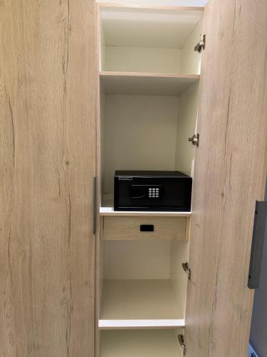 a small cabinet with a black appliance on a shelf at Hamsun Apart Hotel Clifton in Karachi
