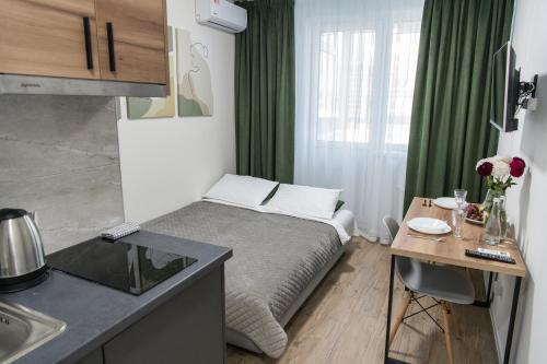 a small room with a bed and a table and a kitchen at Апартаменти MYFREEDOM поруч із метро Бориспільська in Kyiv