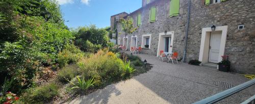 a walkway between two buildings with chairs and plants at Hotel Des Négociants in Lamastre