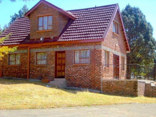 uma casa de tijolos com um telhado vermelho em Khutsong Lodge 