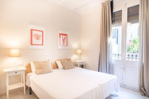 een witte slaapkamer met een bed en een raam bij Gracia12 in Barcelona