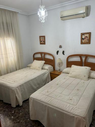 1 dormitorio con 2 camas y lámpara de araña en Villa Rafael, en Puente del Obispo