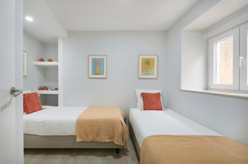 two beds in a room with white walls and a window at Renovated House Near Beaches, By TimeCooler in Setúbal