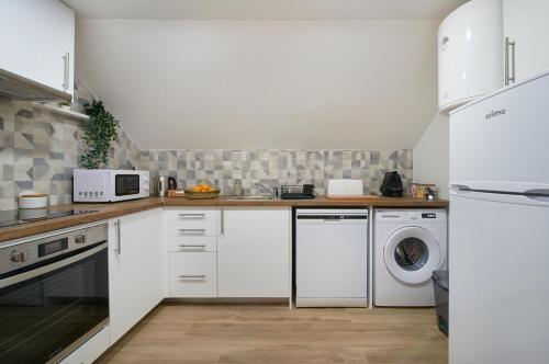 a kitchen with white cabinets and a washer and dryer at Renovated House Near Beaches, By TimeCooler in Setúbal