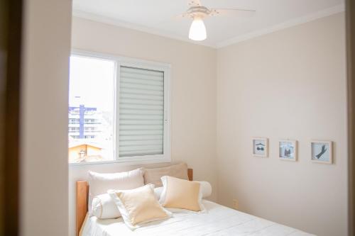 a bedroom with a bed with white sheets and a window at Paramar Praia Grande in Ubatuba