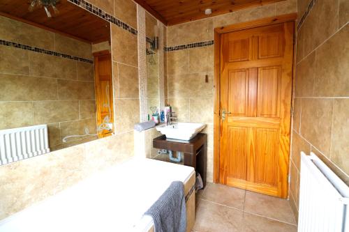 ein Badezimmer mit einem Waschbecken und einer Holztür in der Unterkunft St James's Rd in Belfast